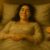 A smiling woman lies in bed with cut oranges and a symbolic wellness item nearby, suggesting comfort, self-care, and personal pleasure.