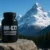 Black supplement bottle labeled MK-677 Growth Hormone Secretagogue placed on a rock with snow-covered mountains and pine trees in the background.