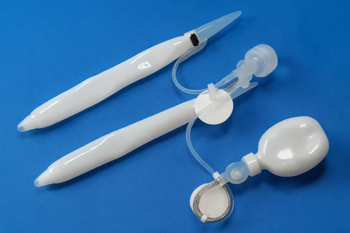 The image shows two vacuum erection devices (VEDs), which are used as non-invasive treatments for erectile dysfunction. The devices consist of a cylindrical chamber (likely made of plastic) with a vacuum pump attached. One device has a bulb for creating suction, and the other appears to have a flexible tubing system, likely used to apply the vacuum to the penis for enhancing blood flow. These devices help men with ED by improving circulation to the penis, which can assist in achieving and maintaining an erection